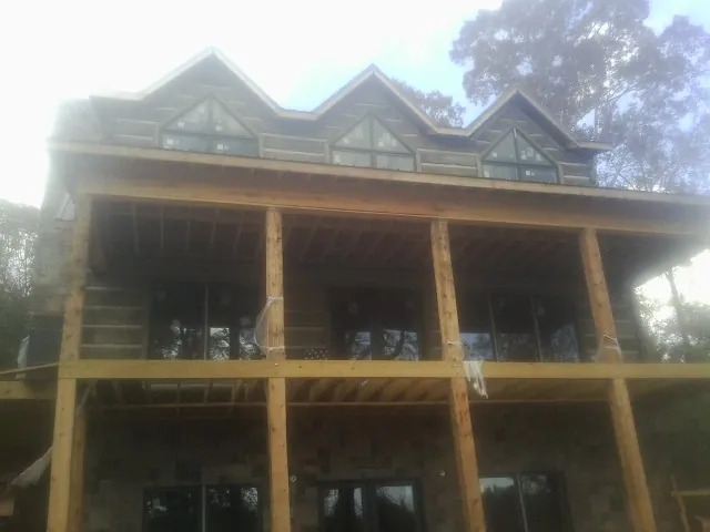 Dormers and porch framing on a large log home under construction — Roof Coating work by our crew in Fromberg