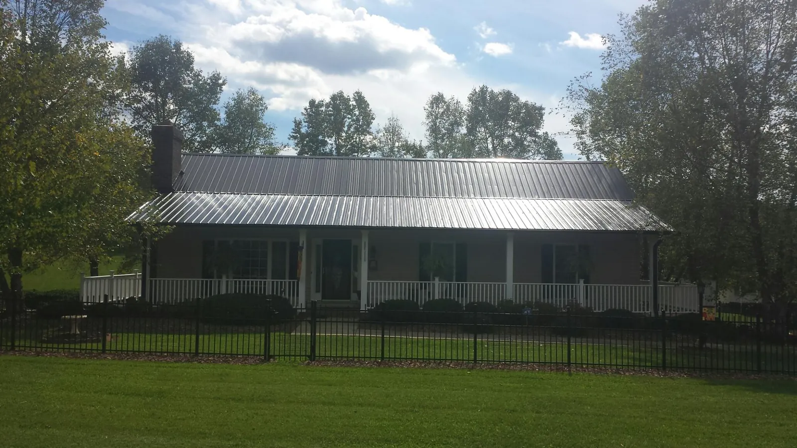 Gray metal roof on a brick ranch with a full width front porch — Gutter Guard Installation work by our crew in Fromberg