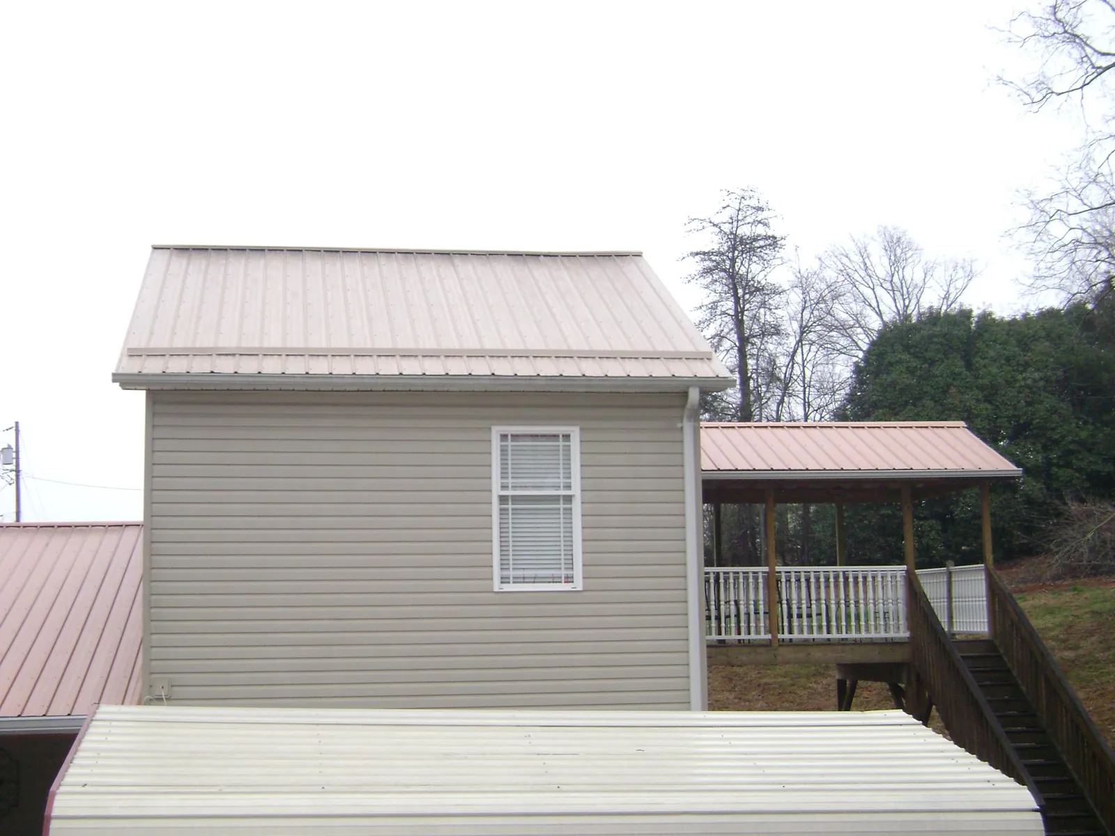 Tan metal roofs on a two story addition and attached porch, from a Roof Replacement job in Fromberg
