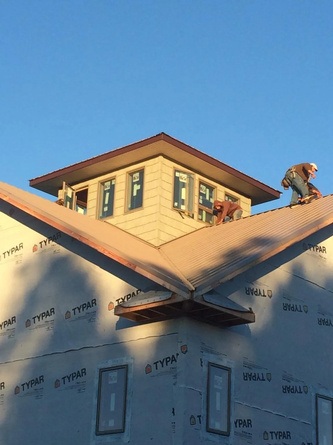 Roofers working around a rooftop cupola on a new metal roof at sunset — Roof Waterproofing in Fromberg by Roofing Brothers